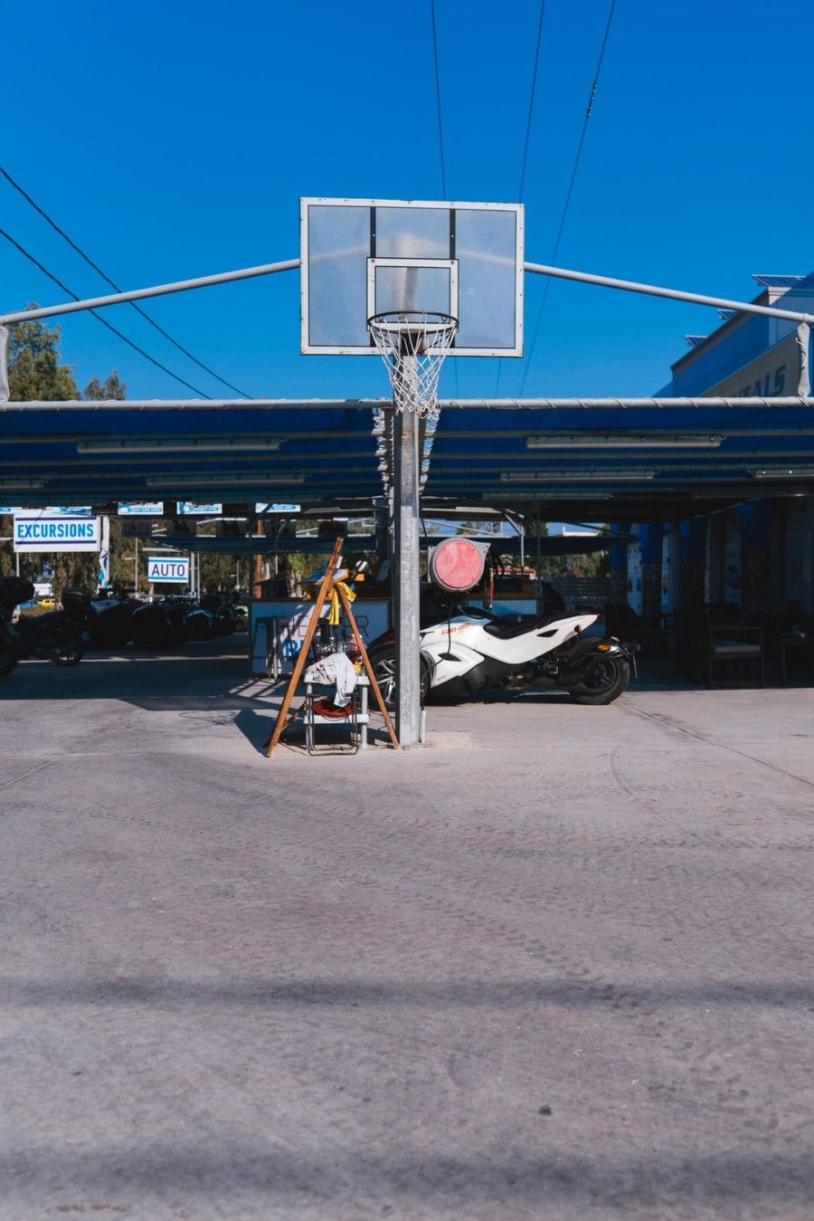 basketball-system-in-front-of-white-sports-bike-parked-under-blue-roofed-space-during-daytime