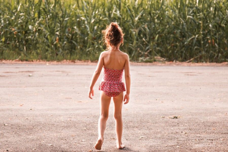 girl-wearing-onepiece-standing-beside-corn-plant-during-daytime