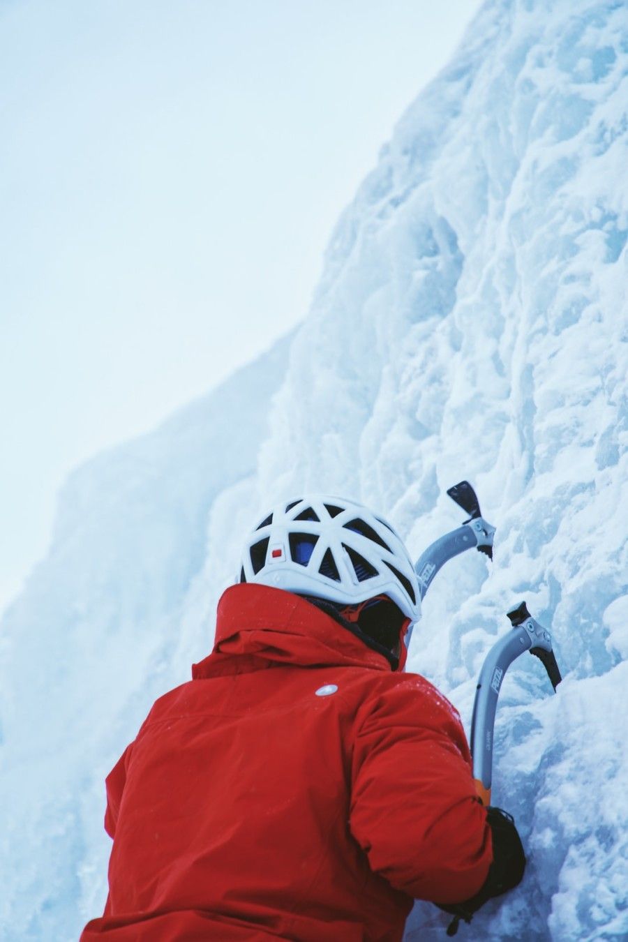 person-in-red-jacket-while-climbing-ice-wall-at-daytime