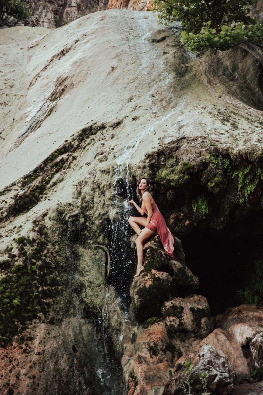 woman-sitting-on-rock-under-waterfalls