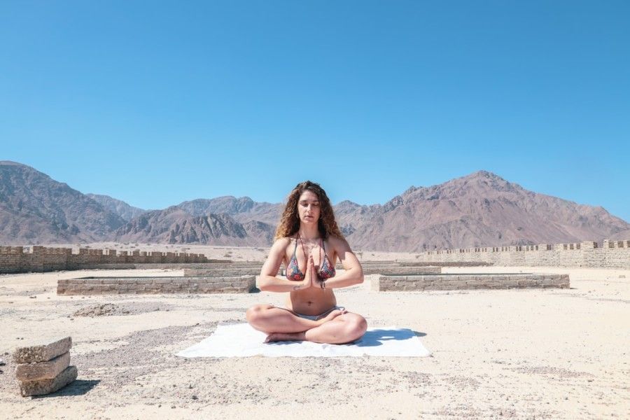 woman-wearing-two-piece-meditating-under-blue-sky-during-daytime
