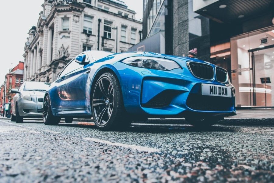 blue-bmw-coupe-parked-on-roadside-in-front-of-building