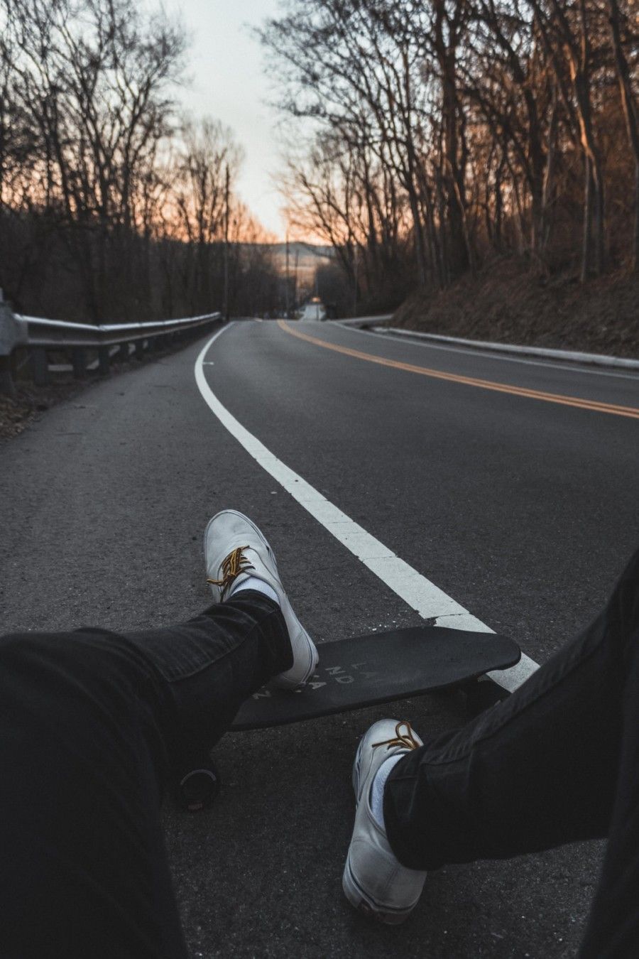 person-sitting-on-road-with-longboard
