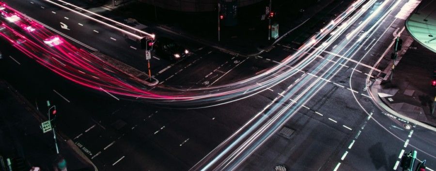 red-and-white-car-lights-streaking-at-street-corner
