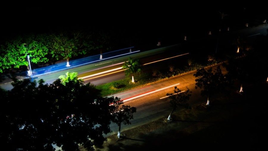 time-lapse-photography-of-cars-passing-by-on-road-near-trees-during-night