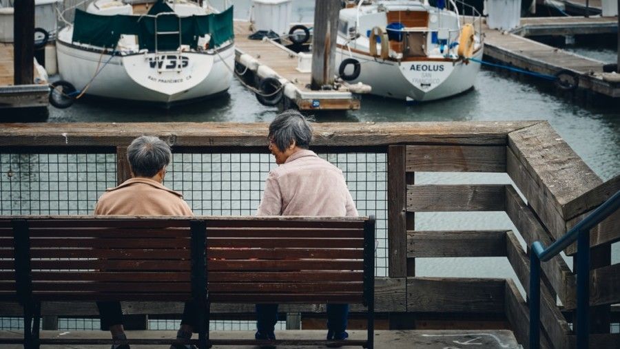 two-person-sitting-in-bench-near-boat-during-daytime