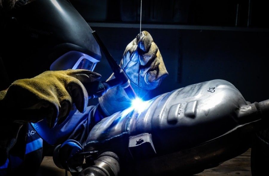 man-wearing-welding-helmet-welding-on-grey-metal-tank