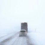 white-car-behind-a-truck-on-snowy-road